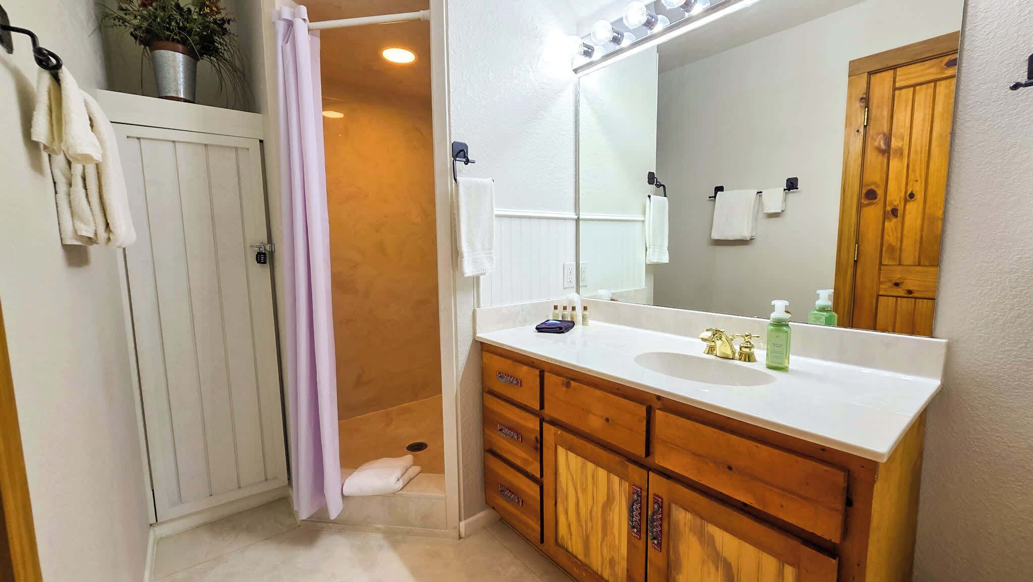 A bathroom with a wooden vanity, a large mirror, and a shower curtain.