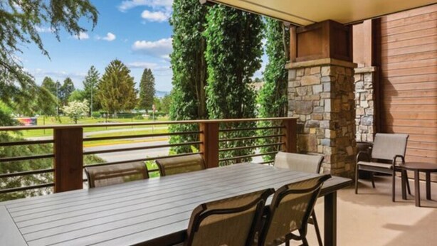 An outdoor patio with a stone fireplace, a table, and chairs.