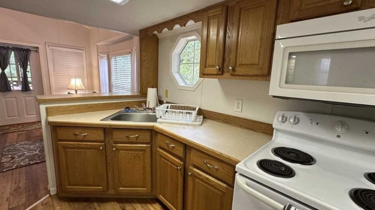 A kitchen with wooden cabinets, a white stove, and a microwave.