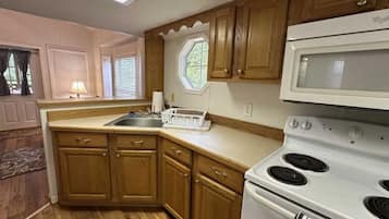 A kitchen with wooden cabinets, a white stove, and a microwave.