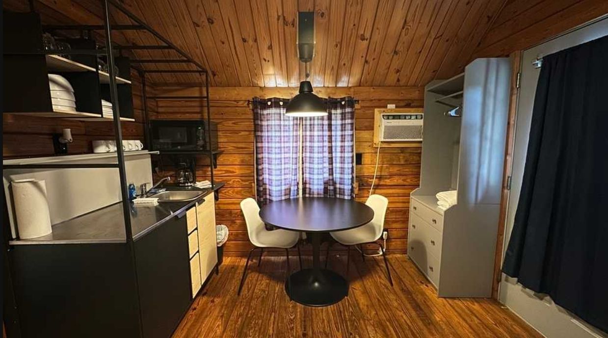 A compact kitchen with a dining table, chairs, and a microwave.