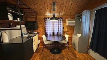 A compact kitchen with a dining table, chairs, and a microwave.