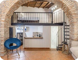 Ein Loft-Zimmer mit Küchenzeile, einem Esstisch und einem blauen Stuhl.
