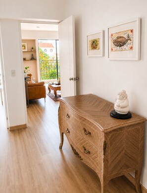 Ein Zimmer mit einer h ölzernen Kommode, einer kleinen Statue und zwei gerahmten Kunstwerken an der Wand.