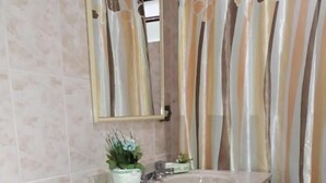 Ein Badezimmer mit einer Badewanne, einem Waschbecken, einem Spiegel und einer Duschvorhang.