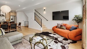 A modern living room with a sofa, a glass coffee table, a cowhide rug, and a staircase. - 3BR/3.5BA Rooftop Home + Private Flat | Tennyson (Denver)