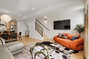 A modern living room with a sofa, a glass coffee table, a cowhide rug, and a staircase. - 3BR/3.5BA Rooftop Home + Private Flat | Tennyson (Denver)