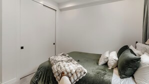 A bedroom with a bed, pillows, a blanket, a door, and a light fixture. - 3BR/3.5BA Rooftop Home + Private Flat | Tennyson (Denver)