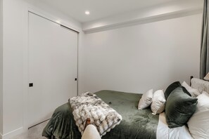 A bedroom with a bed, pillows, a blanket, a door, and a light fixture. - 3BR/3.5BA Rooftop Home + Private Flat | Tennyson (Denver)