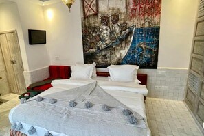 A hotel room with a bed, a red accent wall, a large abstract painting, and a tiled floor. - BCK Art Riad (Marrakech)