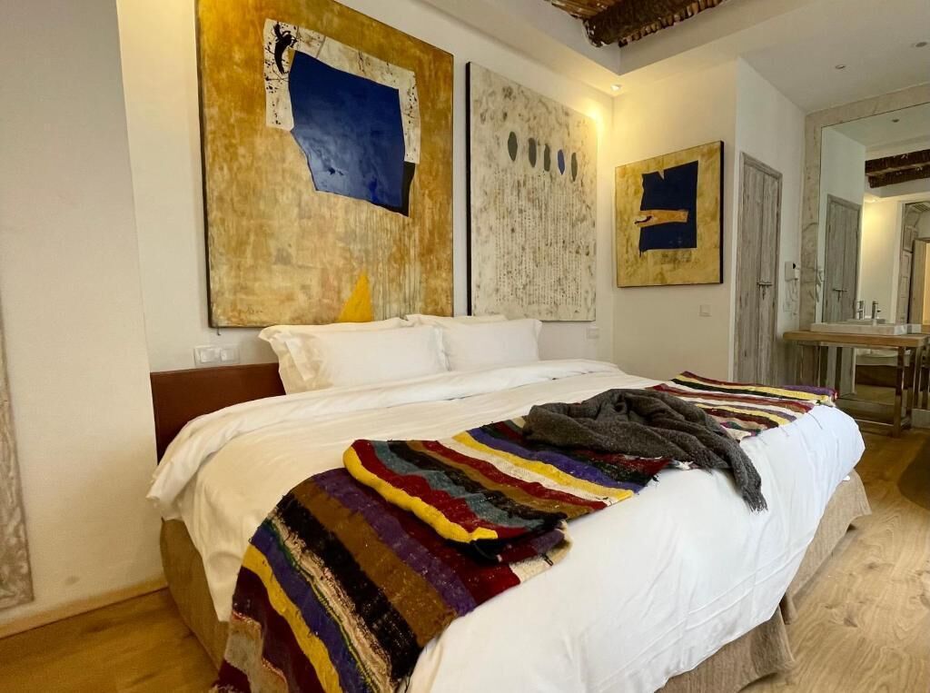 A bedroom with a large bed, a wooden headboard, and a colorful striped blanket.
