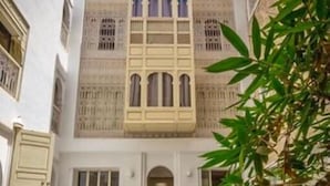 A courtyard with a pool, traditional cushions, and a building with arched windows. - BCK Art Riad (Marrakech)