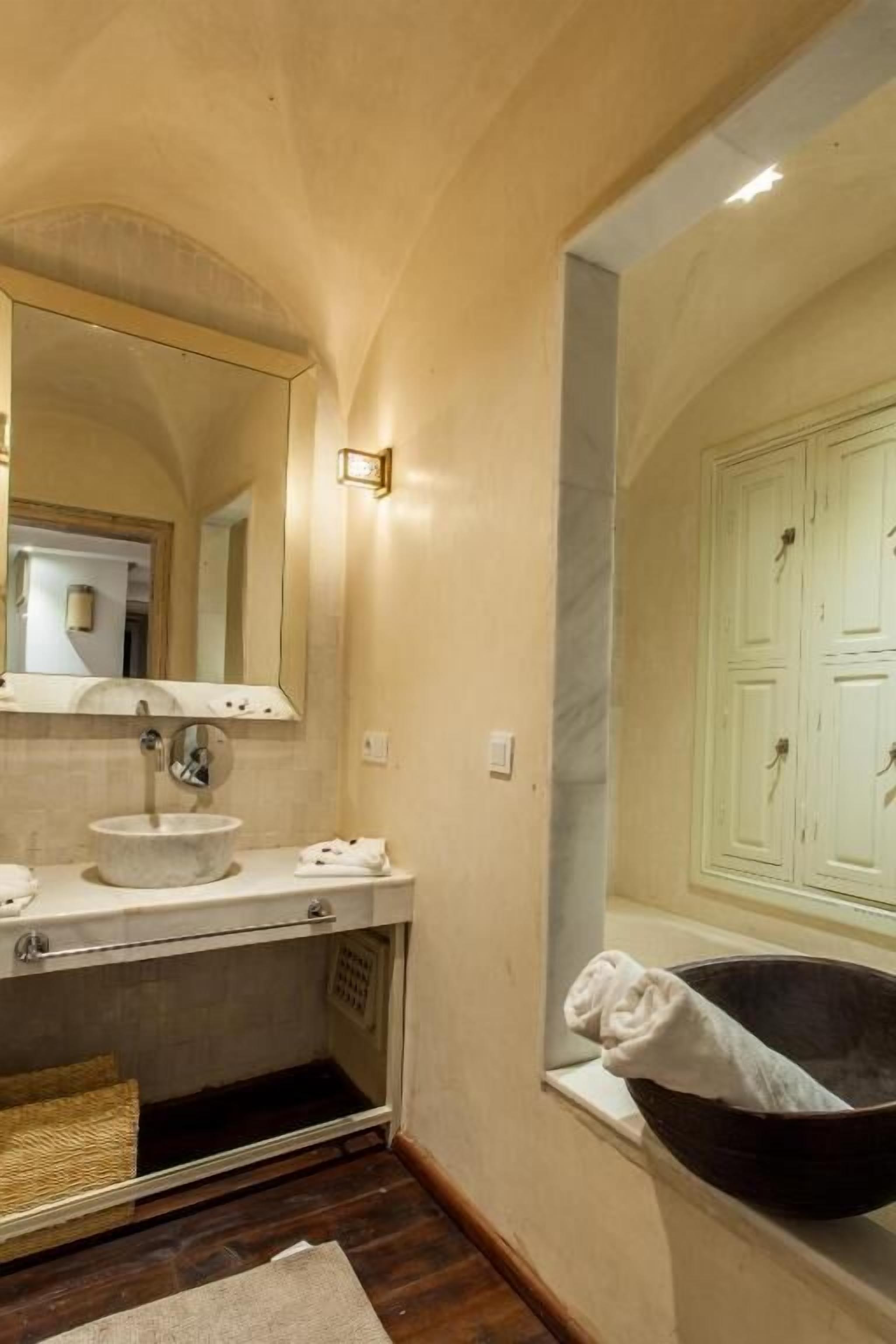 A bathroom with a sink, mirror, and bathtub.