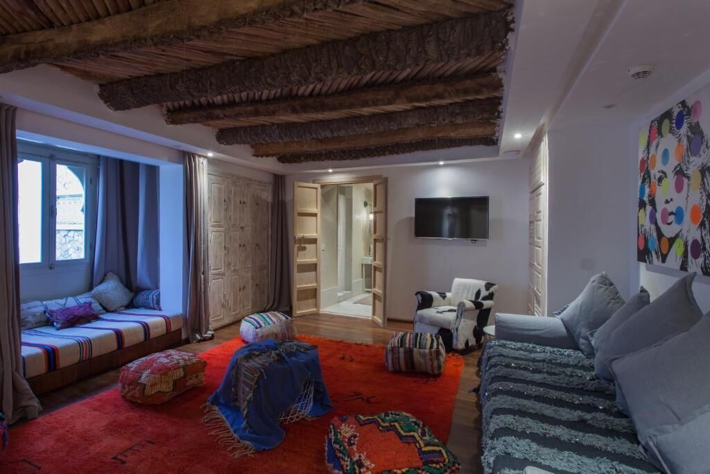 Ein gemütliches Wohnzimmer mit einer Couch, einem Fernseher und einem farbenfrohen Teppich.