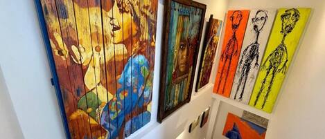 A staircase with a handrail and steps, leading to a landing where artworks are displayed on the wall.