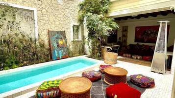 Ein Innenhof mit Pool, Sitzgelegenheiten im Freien und einer Steinmauer.
