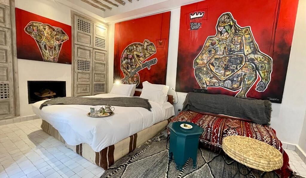A bedroom with a bed, a small table, a decorative wall, and a fireplace.
