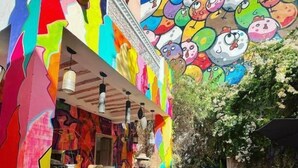 An outdoor seating area with a colorful mural, tables, and chairs. - bck art riad (Marrakech)