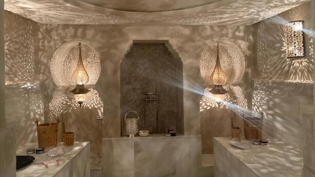 A room with a central arched doorway, two wall-mounted lamps, and a ceiling light fixture. - BCK Art Riad (Marrakech)