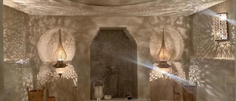 A room with a central arched doorway, two wall-mounted lamps, and a ceiling light fixture.