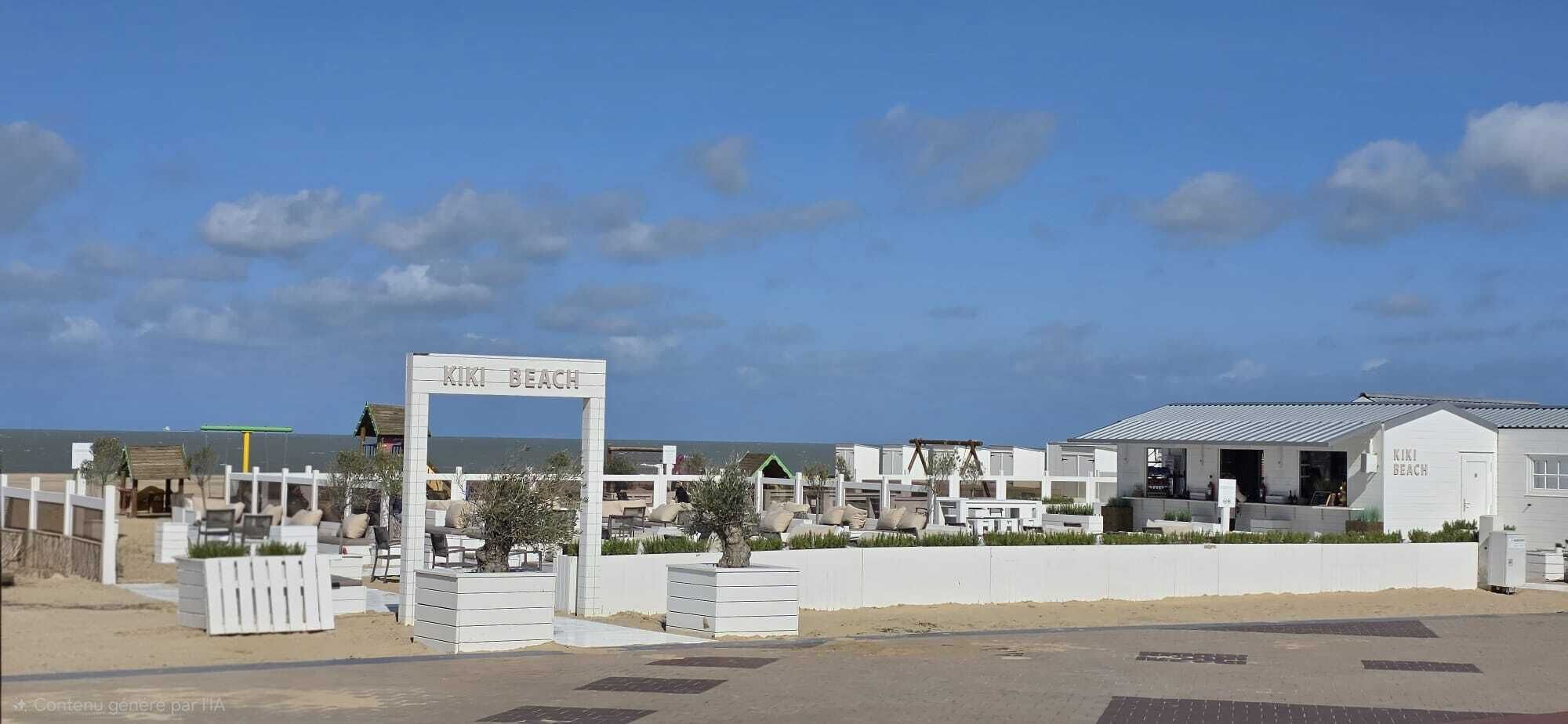 A beachfront property with a sign reading 'KIKI BEACH,' featuring multiple white buildings with flat roofs, some with visible windows and doors.