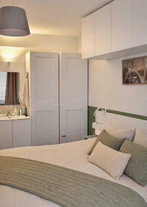 Une chambre d’hôtel comprenant un lit, une table de chevet, une lampe, un miroir et une armoire.