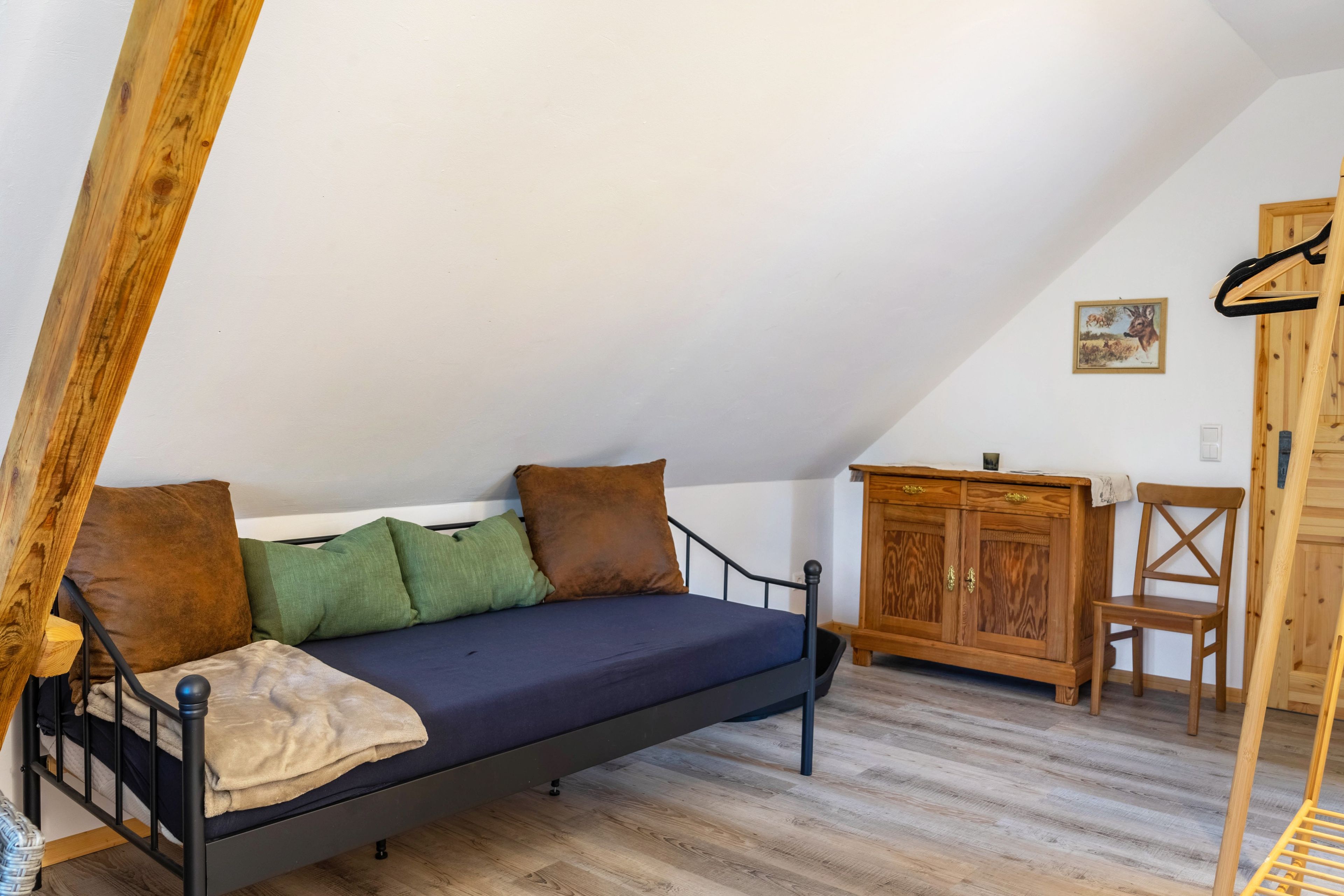 Une chambre à coucher aménagée dans un espace ouvert, avec un lit, une armoire en bois et une chaise.