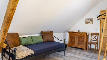 Une chambre à coucher aménagée dans un espace ouvert, avec un lit, une armoire en bois et une chaise.