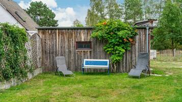 A wooden fence with a bench and two chairs in a backyard.