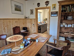 Una mesa de comedor de madera con un atril para el menú, una silla y un mueble de madera con vajilla.