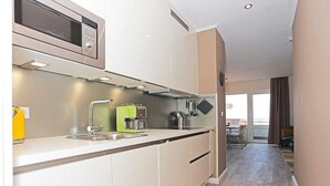 A modern kitchen with a microwave, sink, and green coffee maker. - Apartment Vogelsang in Borkum (Borkum)
