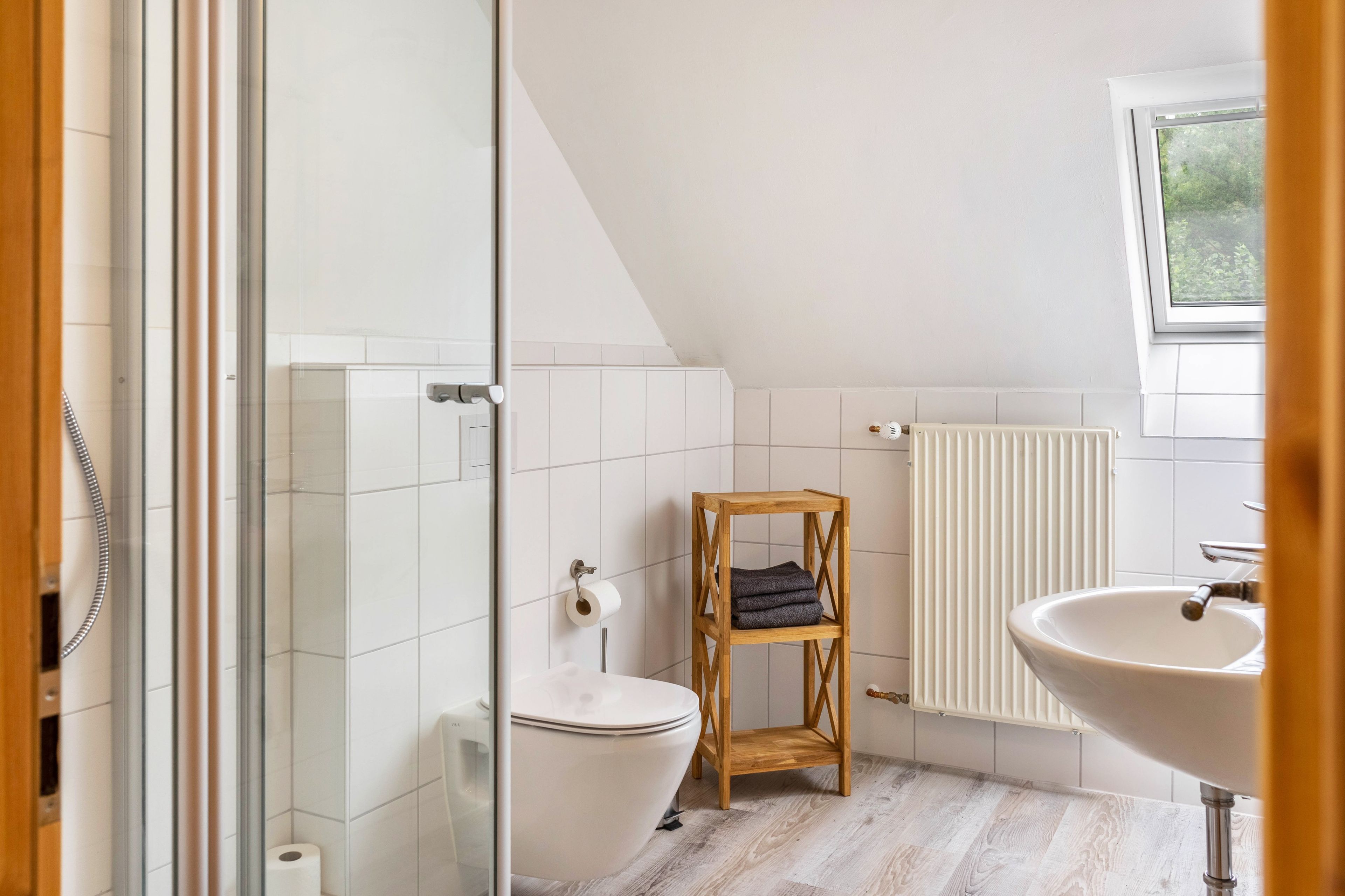 Ein modernes Badezimmer mit Toilette, Bidet und einem Holzregal.