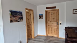 Un pasillo con puertas de madera, un sofá de cuero marrón y dos cuadros en las paredes.