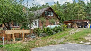 Une maison traditionnelle en bois, avec un toit à pente, une clôture en bois et une pancarte indiquant « Jagdhaus An der Nemitzer Heide ».