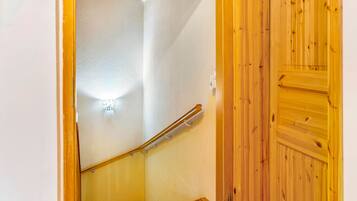 Eine Holztreppe mit Handlauf, einer Wandleuchte und einer Holztür.