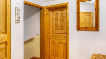 Eine Holztür mit einem Spiegel darüber, ein kleines Schild an der Wand und eine hölzerne Bank.