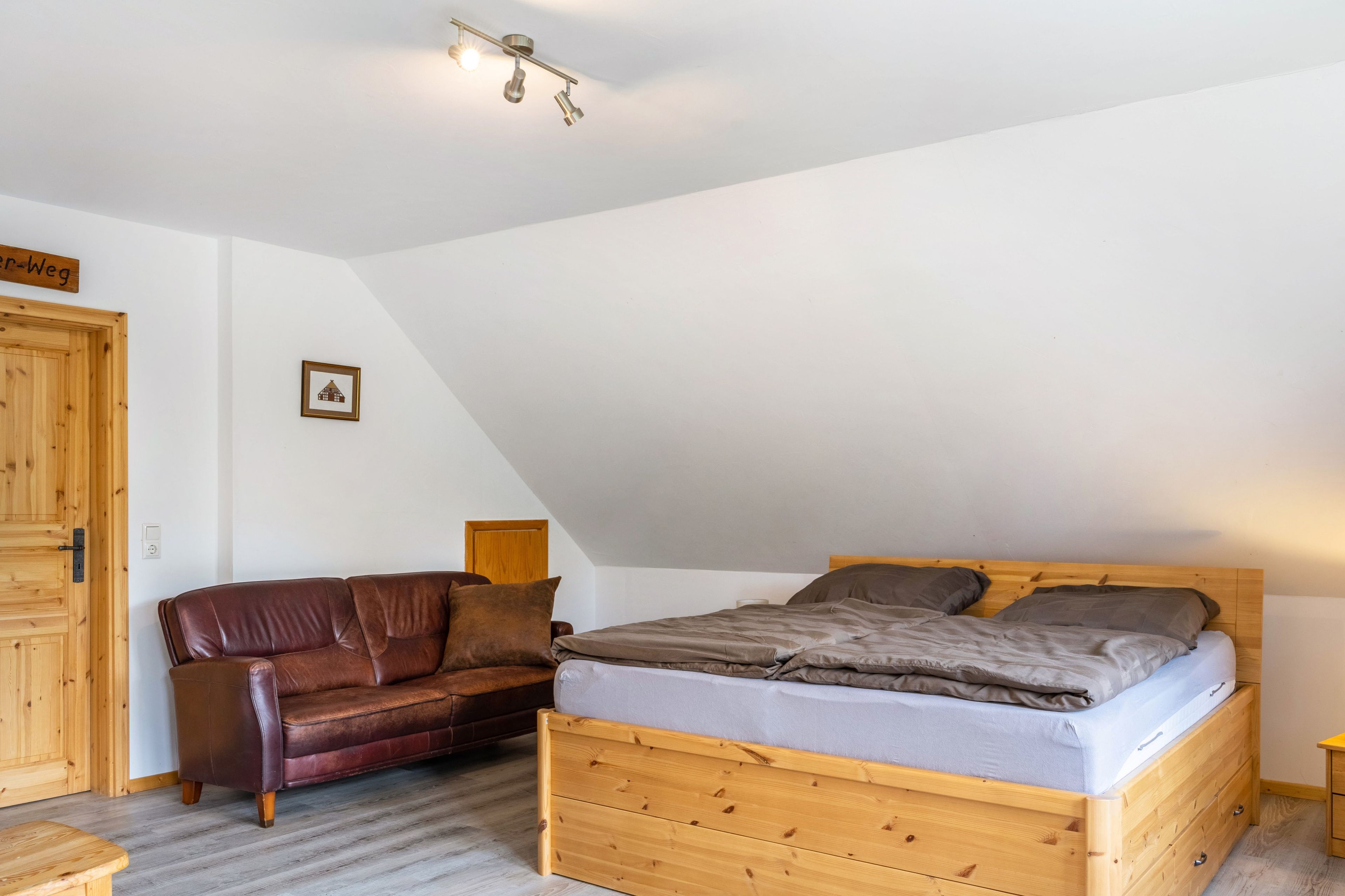 Une chambre à coucher avec un lit en bois, un canapé en cuir et une armoire en bois.