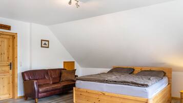 Ein Schlafzimmer mit einem hölzernen Bett, einer Ledersofa und einem Holzschrank.