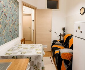 Un espacio habitable compacto con comedor, sofá, una mesita y kitchenette.