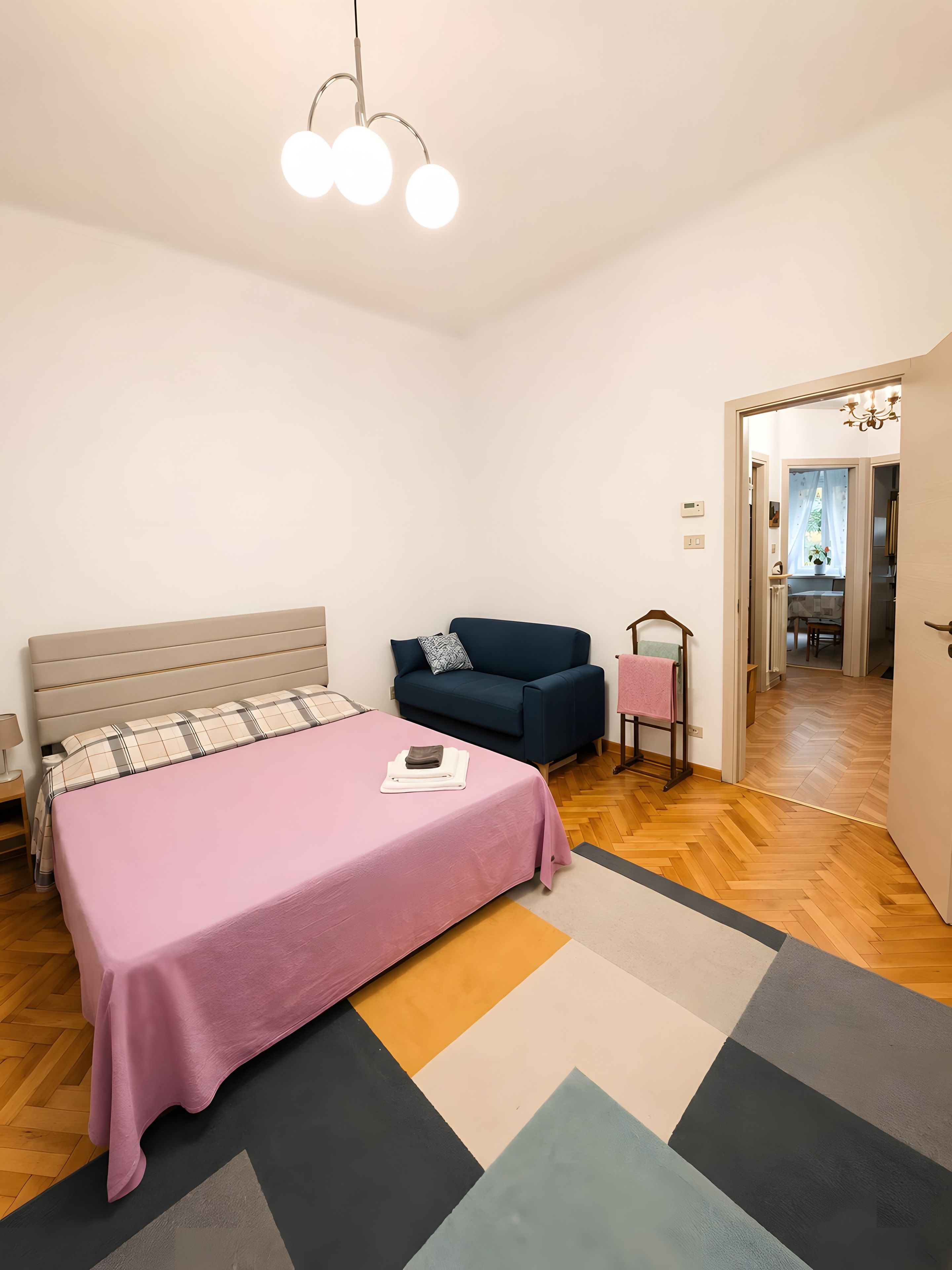 Une chambre à coucher comprenant un lit, un canapé, une table de chevet et un couloir menant à une salle de bain.