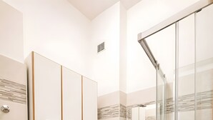 Une salle de bain moderne équipée d’un lave-linge, d’un évier et d’une douche à parois de verre.