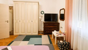 Une chambre à coucher comprenant une armoire, un téléviseur, un miroir, une table de chevet et un lit.