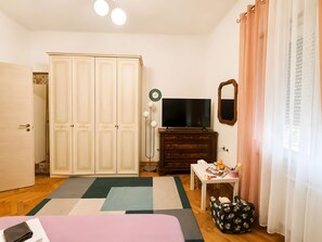 Ein Schlafzimmer mit Kleiderschrank, Fernseher, Spiegel, Nachttisch und Bett.