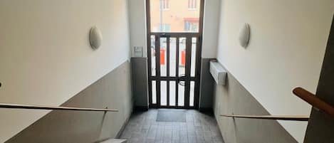 A stairway leading to a door with a view of a building outside.