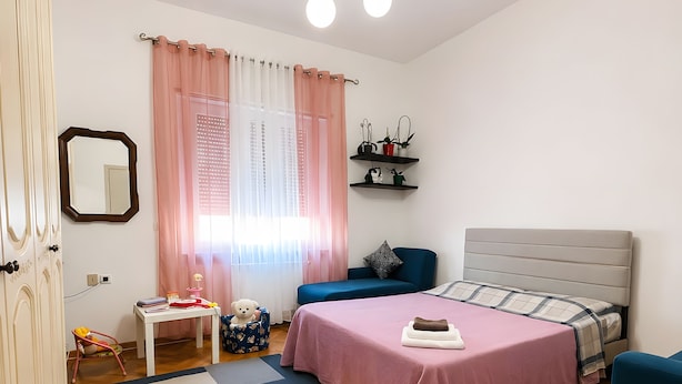 Une chambre à coucher comprenant un lit, une table de chevet, une chaise et un luminaire suspendu.