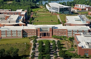 Vista aérea de un campus con varios edificios, césped verde y una plaza circular central.
