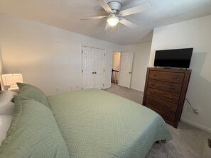 A bedroom with a bed, a dresser, a ceiling fan, and a television. - Johnny’s Place: centrally located & fully loaded! (Raleigh)
