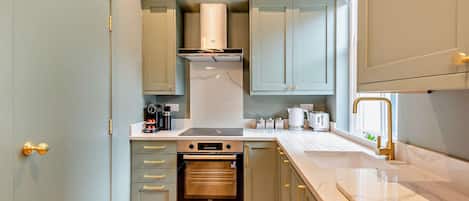 Una cocina compacta con horno integrado, cafetera y tostadora.