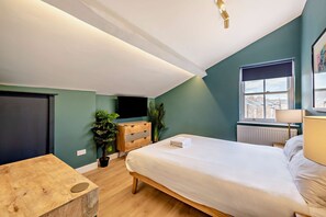 Ein Schlafzimmer mit einem Bett, einer Kommode, einem Fernseher und einem Fenster mit Blick.