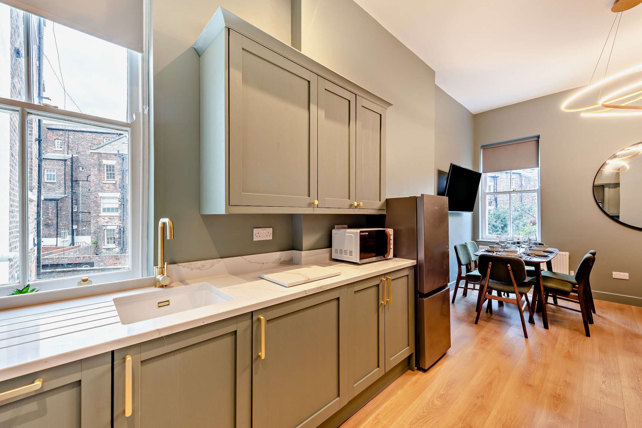 A modern kitchen with grey cabinets, a built-in microwave, and a refrigerator.